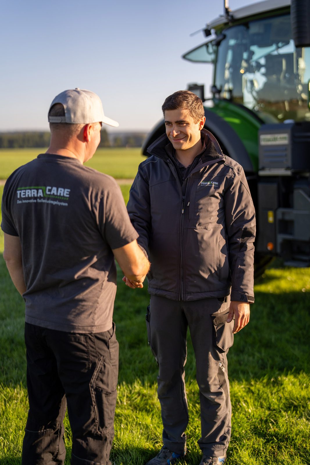 Handschlag zwischen TerraCare-Mitarbeiter und Partner vor einem Traktor